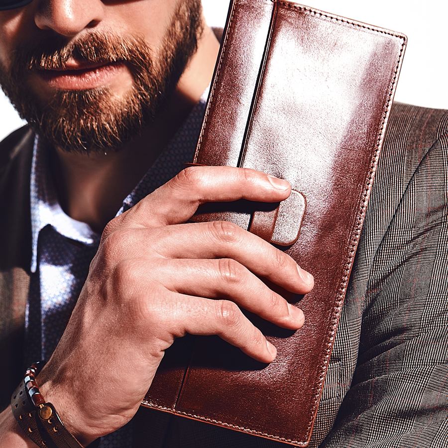 Man in a brown suit holding a chestnut leather long wallet